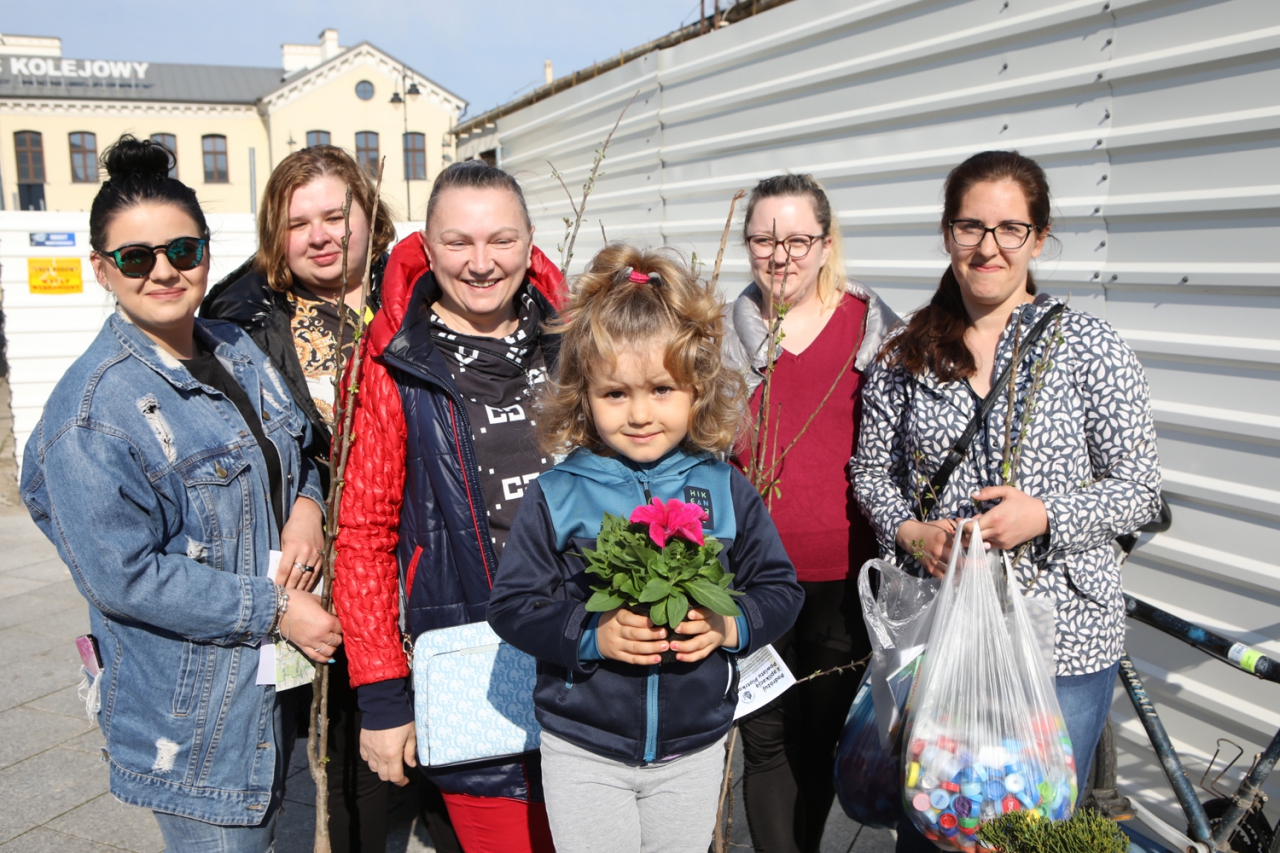 Uśmiechnięte kobiety stoją z sadzonkami drzew i kwiartkami