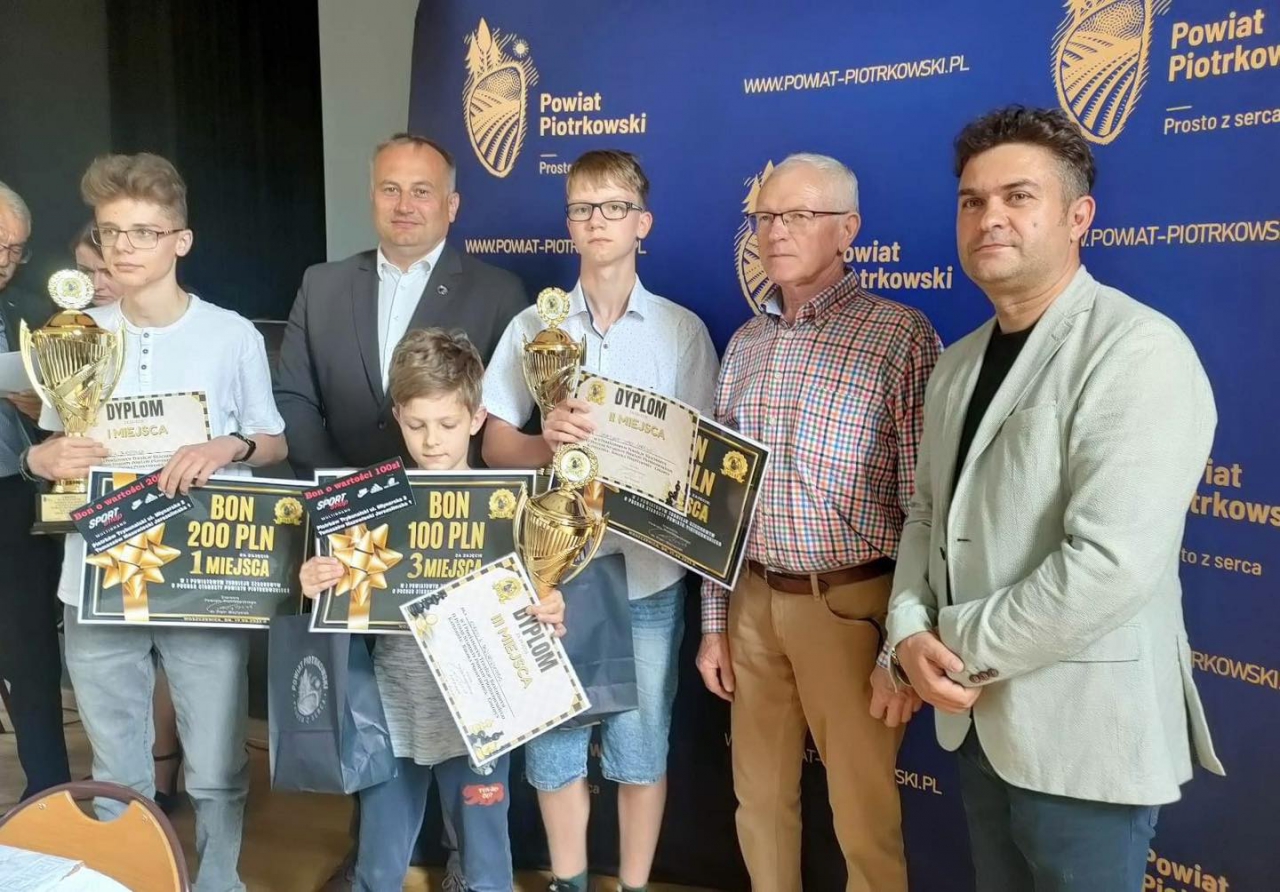 osoby stoją, trzy z pucharem i dyplomami