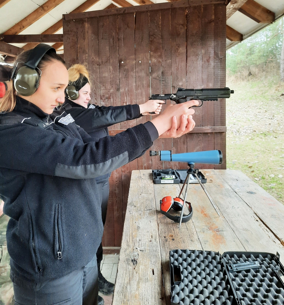 Uczennice szkoły podczas strzelania z broni