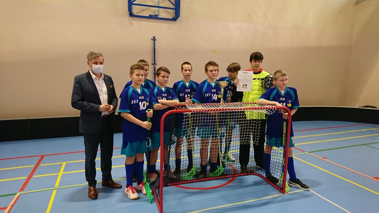 Wicestarosta powiatu Dariusz Magacz wraz z zawodnikami unihokeja stoi przy bramce