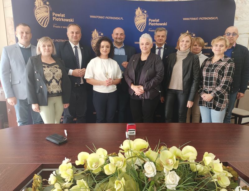 Stowarzyszenia, które otrzymały dofinansowanie wraz z władzami powiatu na tle ścianki Powiatu Piotrkowskiego