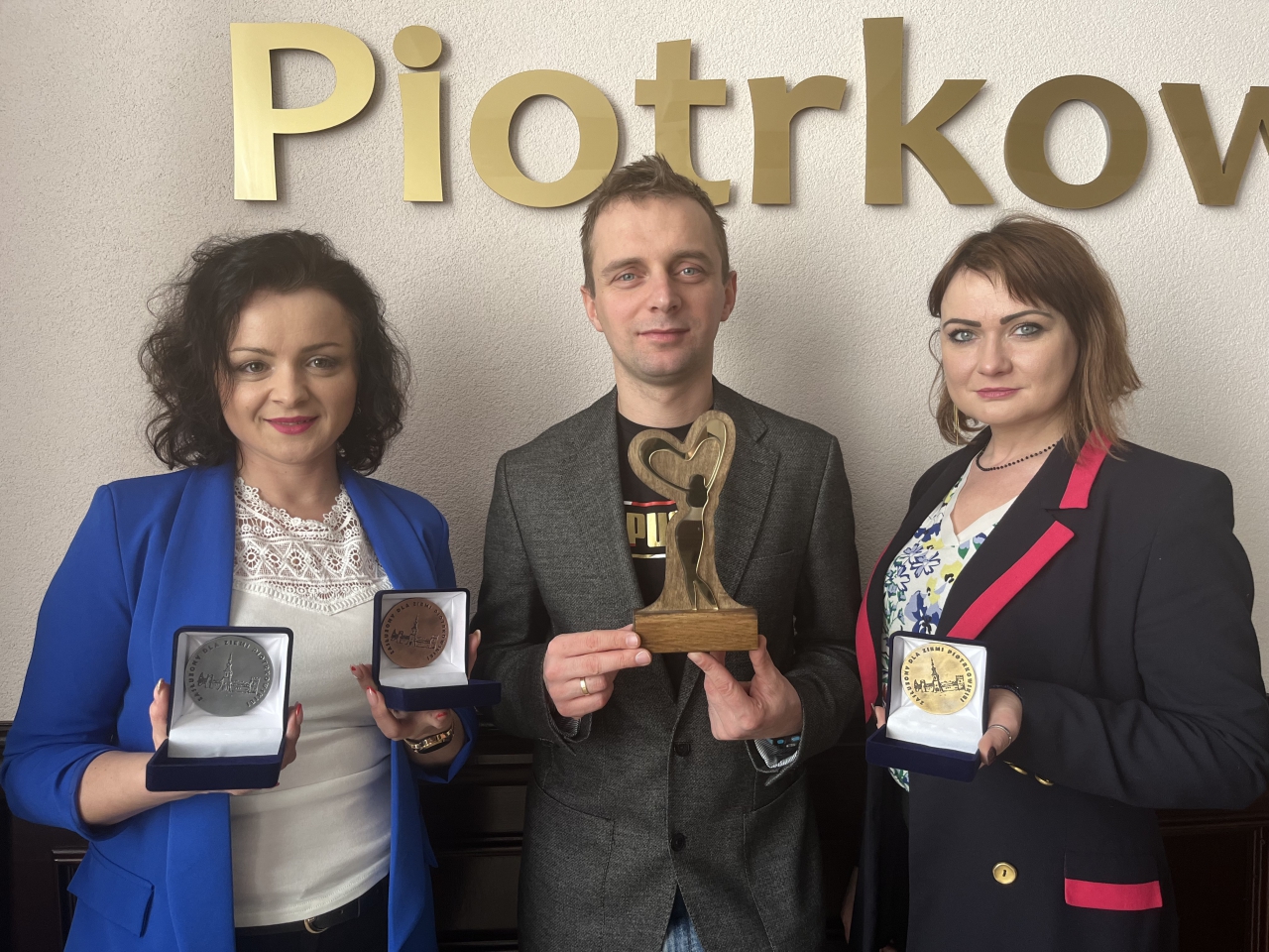 Pracownicy wydziału aktywizacji Społecznej stoją w Sali konferencyjnej Starostwa z medalami oraz statuetką
