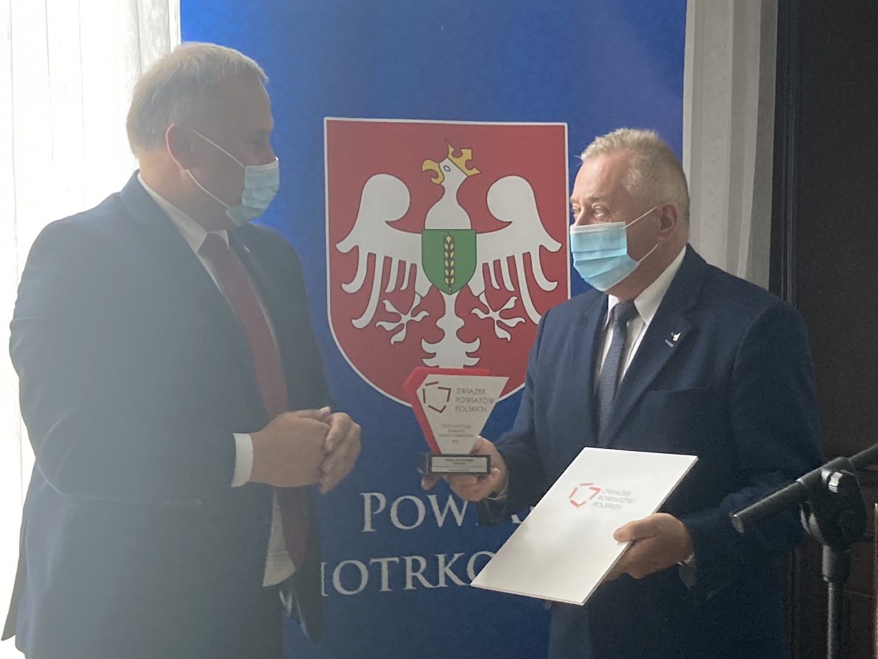Dwóch mężczyzn stoi w sali konferencyjnej.