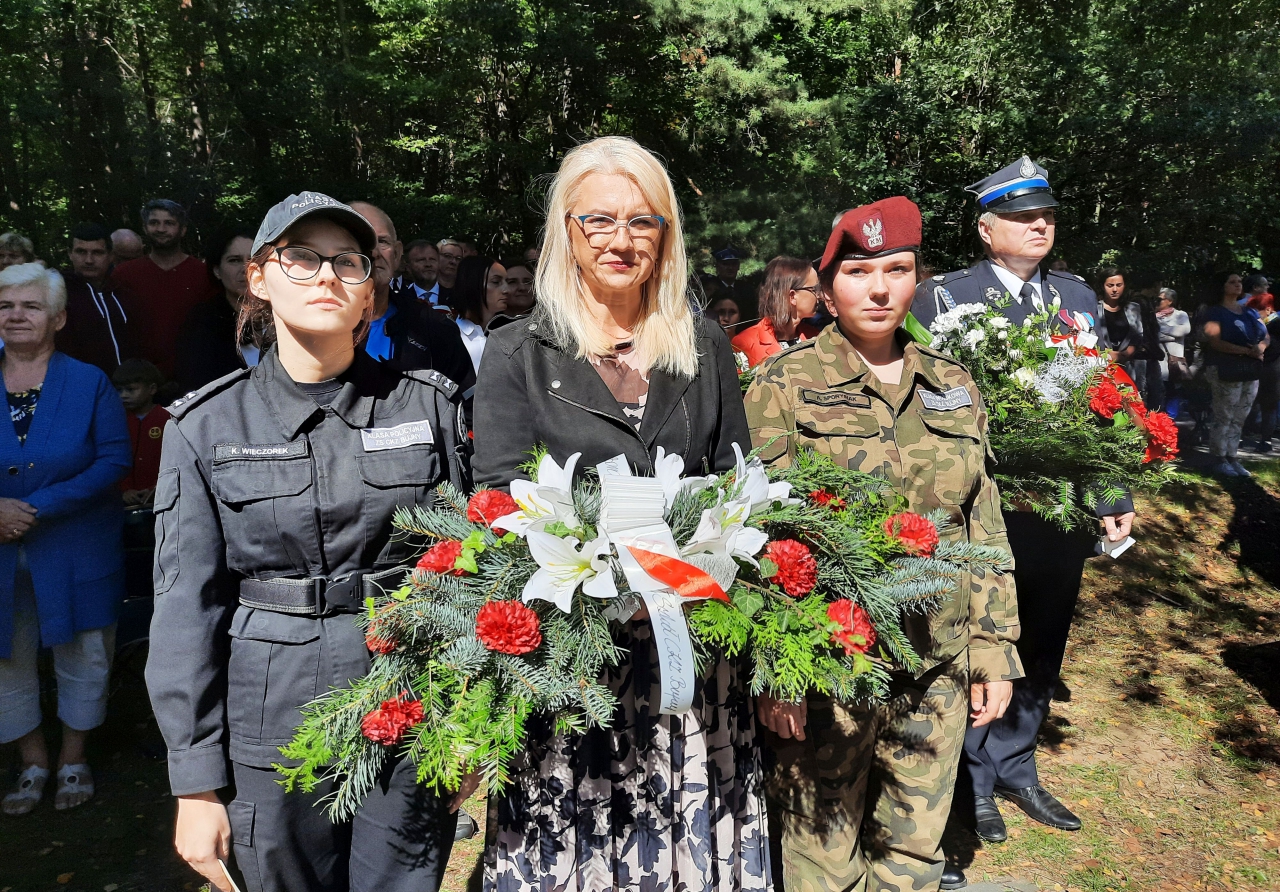 Dyrektor szkoły wraz z uczniami składa wiązanekę kwiatów pod pomnikiem poległych w obronie Gór Borowskich