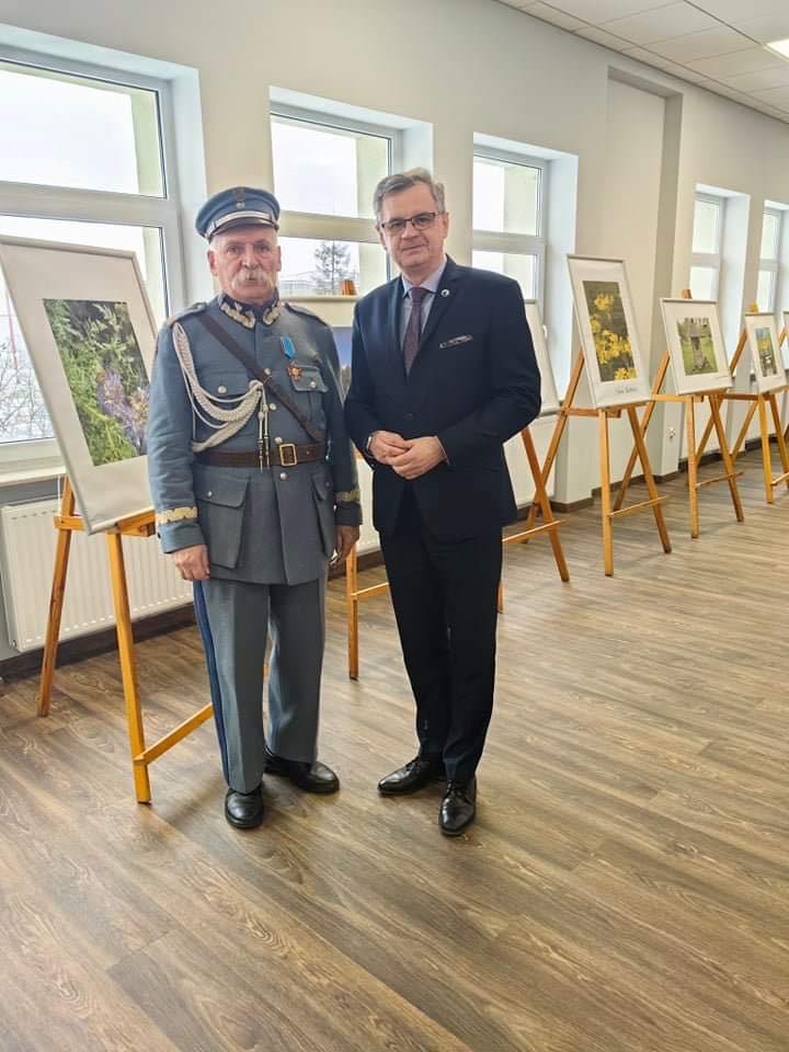 Wicestarosta Dariusz Magacz stoi w siedzibie Starostwa w Końskich z mężczyzną w przebraniu żołnierza. W tle zdjęcia pasiek.