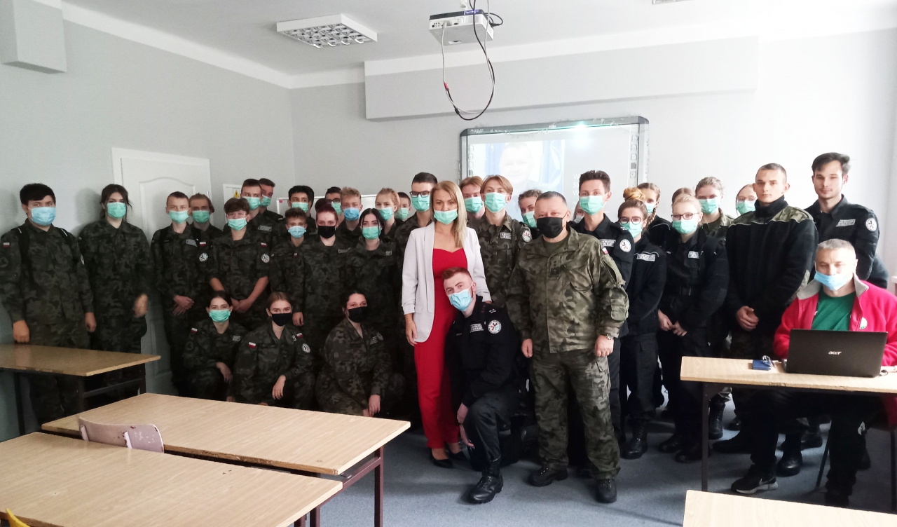 Grupa kilkudziesięciu osób w klasie lekcyjnej.