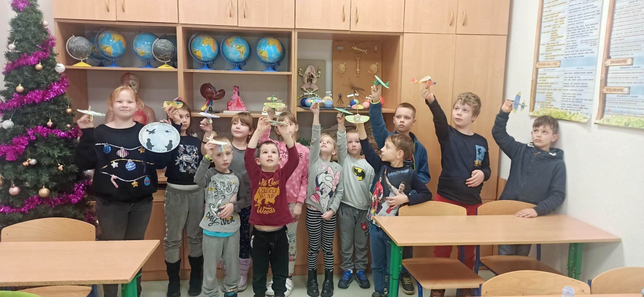 Dzieci znajdują się w pomieszczeniu. obok stoi choinka