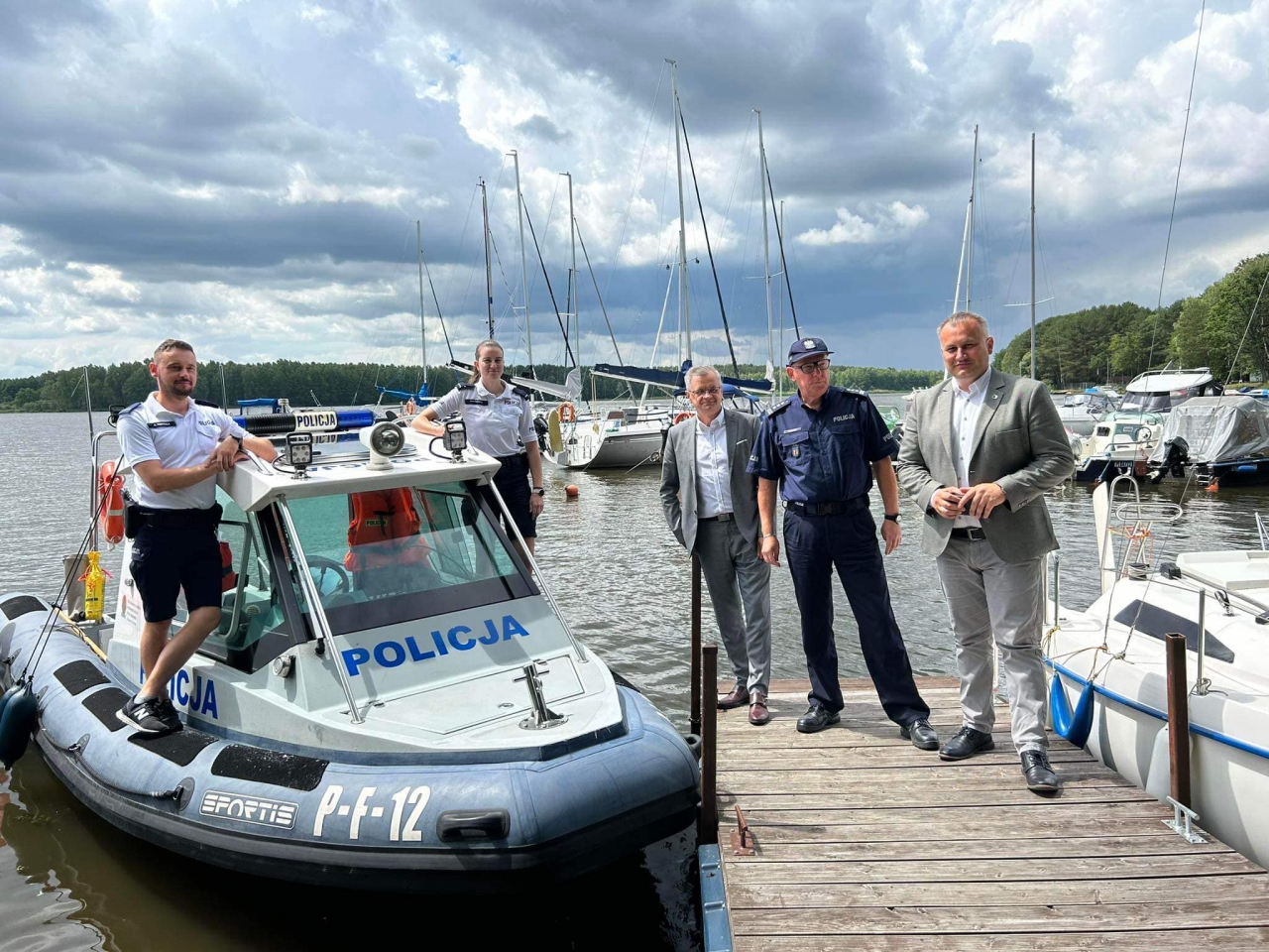 Czterech mężczyzn i kobieta stoi na pomoście Zalewu