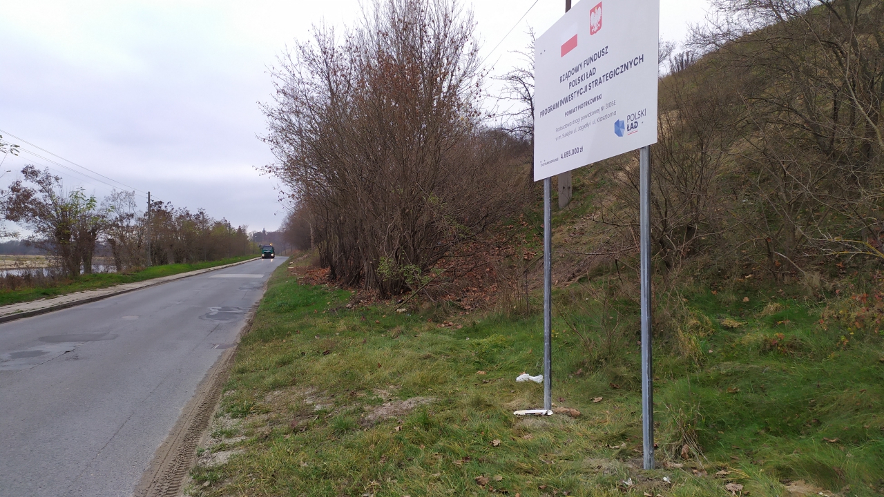 Ulica Klasztorna w Sulejowie. Przy drodze ustawiona jest tablica informacyjna