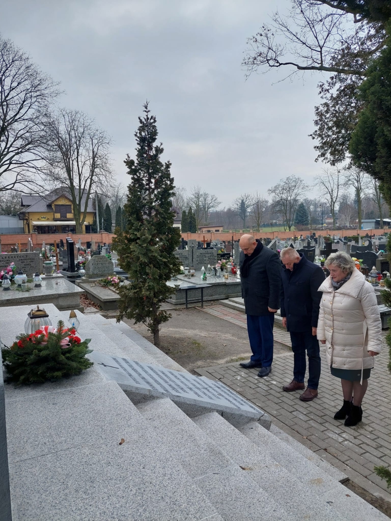 Przedstawiciele Powiatu Piotrkowksiego stoją przed grobem Powstańców Styczniowych na cmentarzu w Piotrkowie Trybunalskim.