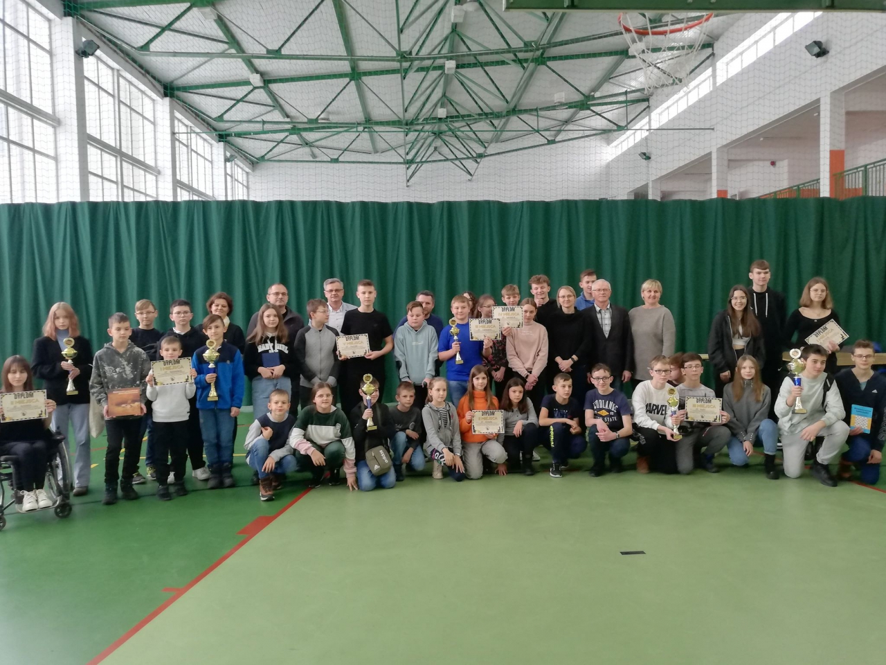 hala sportowa dzieci biorące udział w Igrzyskach Szachowych pozują ze otrzymanymi pucharami i dyplomami