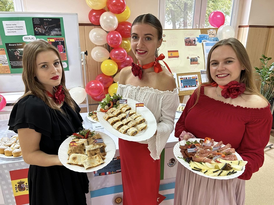 Uczennice stoją i trzymają w rękach talerze z potrawami
