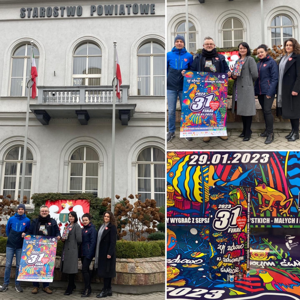 Pracownicy Starostwa stoją przed budynkiem Starostwa z puszką i plakatem promującymi 31. finał WOŚP.
