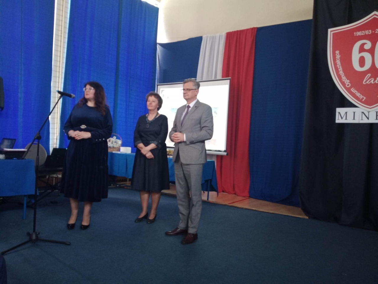 Wicestarosta Dariusz Magacz oraz przedstawiciele Szkoły stoją na scenie w budynku. W tle napis 60 lat minęło.