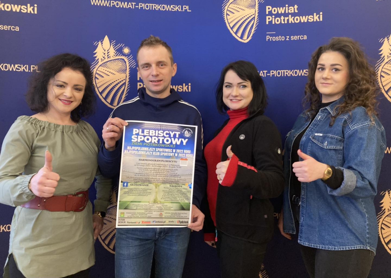 Pracownicy Wydziału Aktywizacji znajdują się w sali konferencyjnej Starostwa z plakatem promującym Plebiscyt Sportowy Ziemi Piotrkowskiej. W tle ścianka z logo Powiatu Piotrkowskiego Prosto z serca.