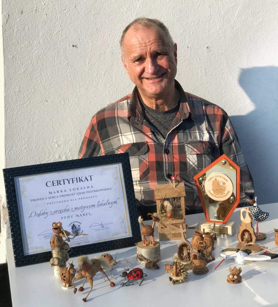Producent ozdób z orzecha wraz ze swoimi produktami, certyfikatem Marki lokalnej prosto z serca przyznanym oraz statuetką z napisem powiat Piotrkowski prosto z serca. Produkt Ziemi Piotrkowskiej.