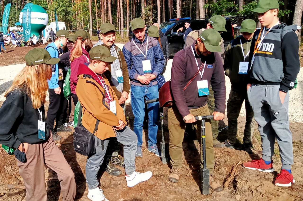 Uczestnicy akcji obserwują jak prawidłowo zasadzić sadzonkę