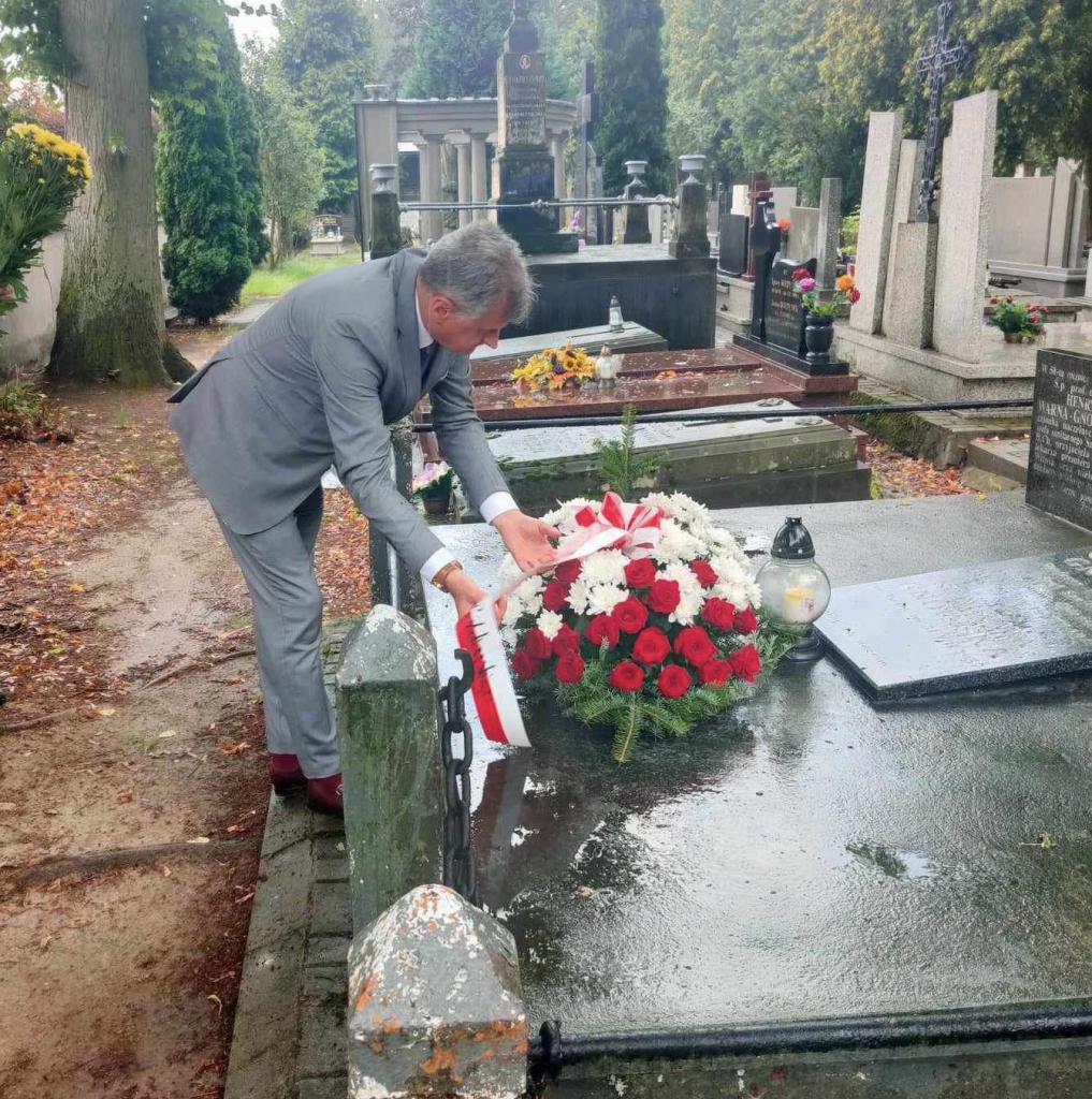 Wicestarosta Magacz układa wiązankę kwiatów na grobie