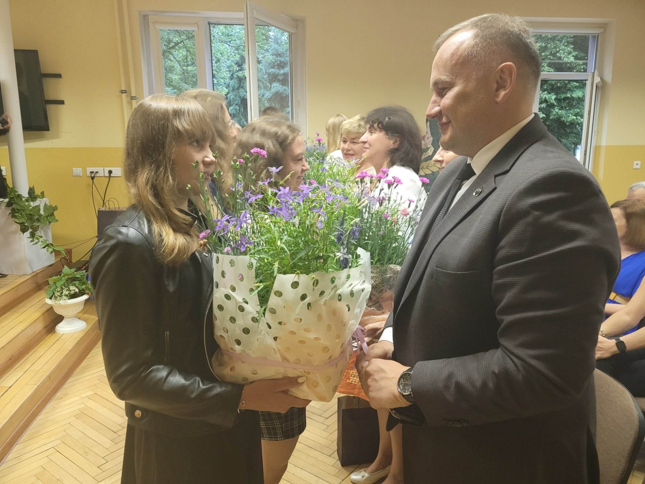 Starosta odbiera kwiaty od uczennicy