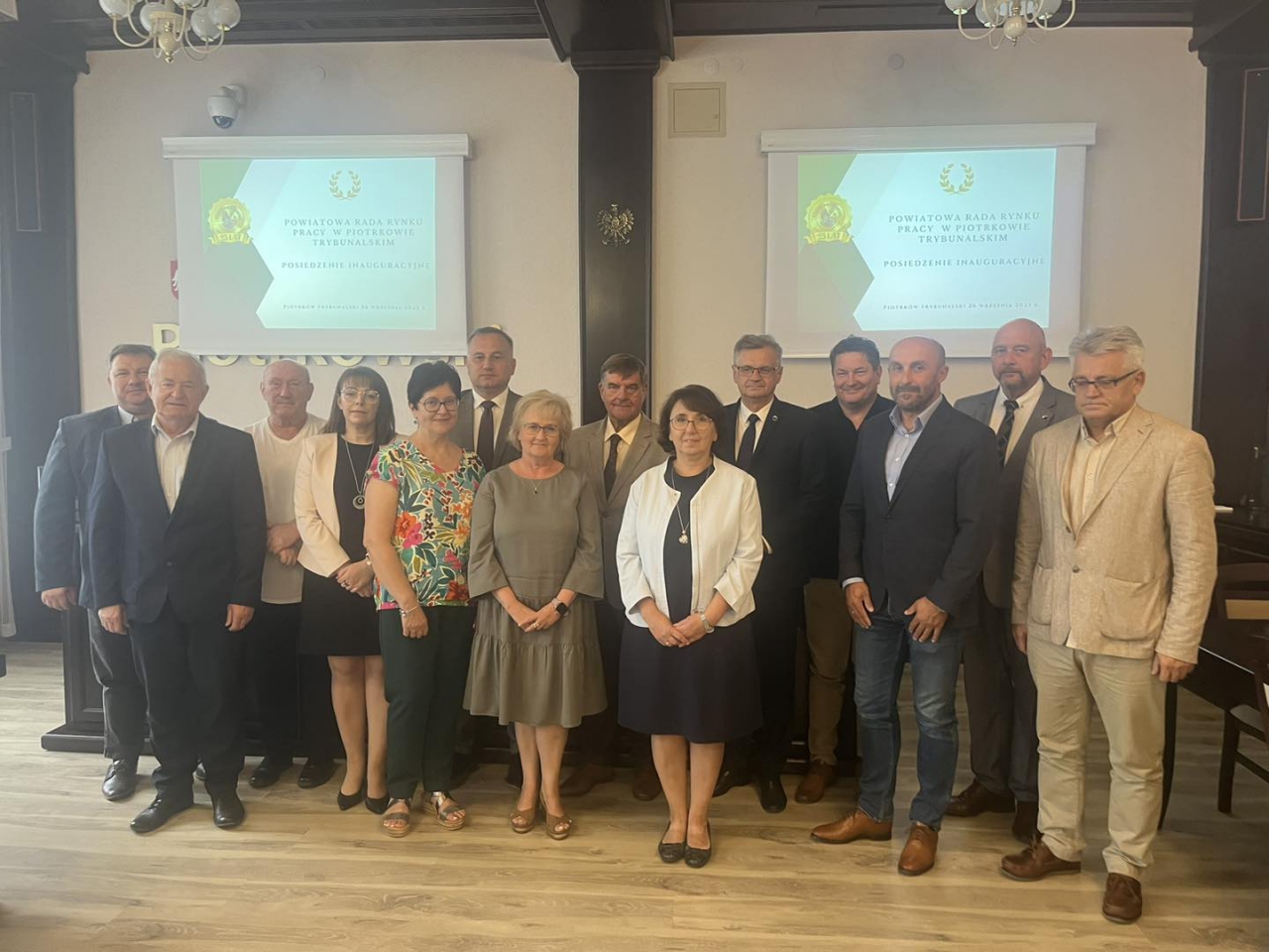 Władze Powiatu, członkowie Rady oraz zaproszeni goście stoją w salo konferencyjnej starostwa.