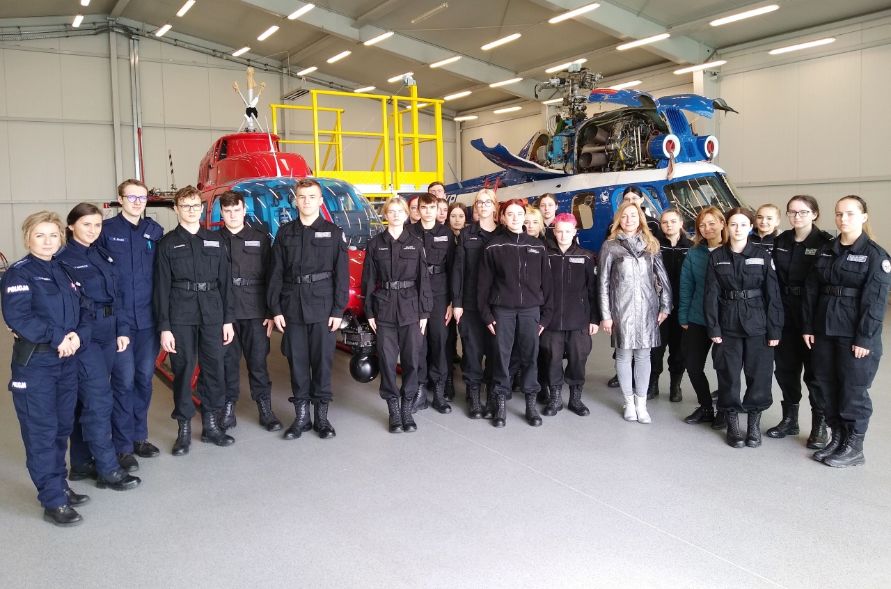 Na zdjęciu uczestnicy wycieczki do garnizonu łódzkiej policji w tle stoją helikoptery