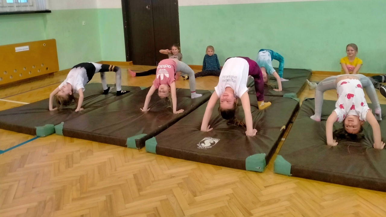Dzieci znajdują się w pomnieszczeniu podczas zajęć sportowych.