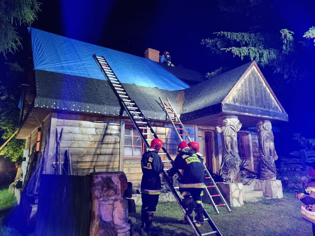 Trzech strażaków zabezpieczają dach budynku mieszkalnego, który został zniszczony przez nawałnicę