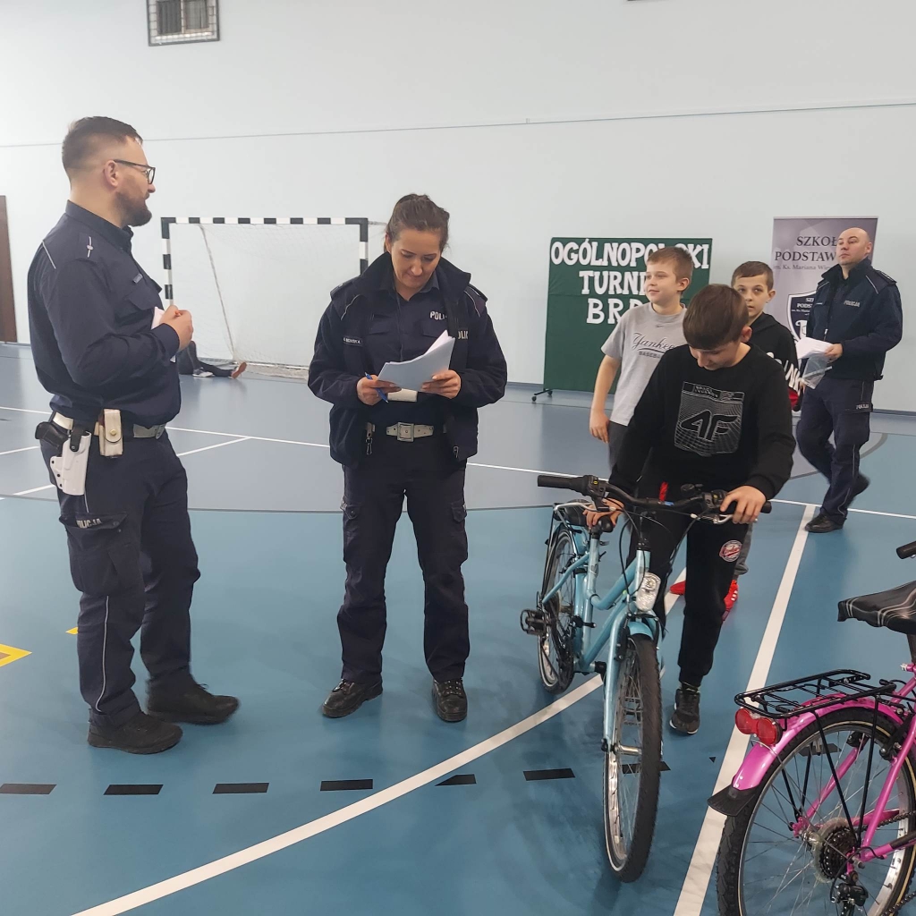Chłopiec trzyma rower obok stoją policjanci
