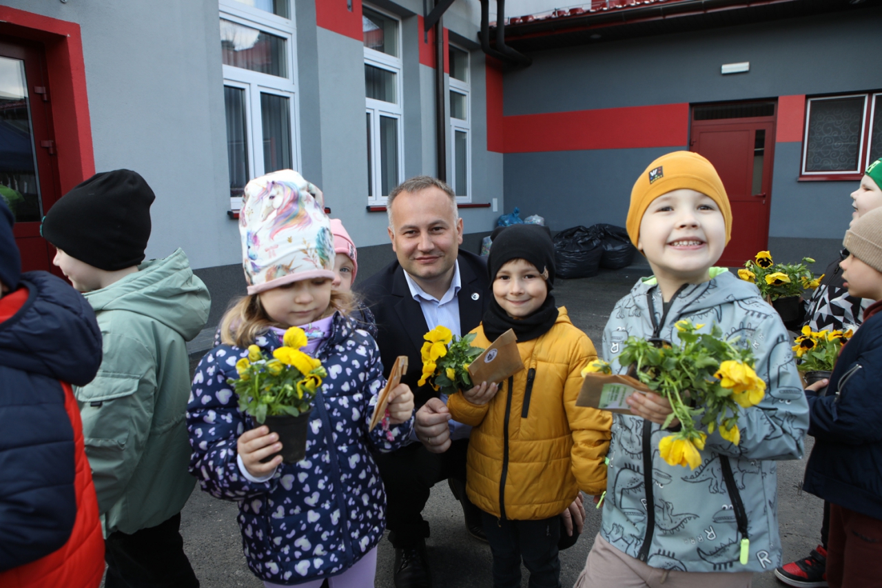 Dzieci z&nbsp;kwiatami wraz ze Starostą Wojtysiakiem który kuca